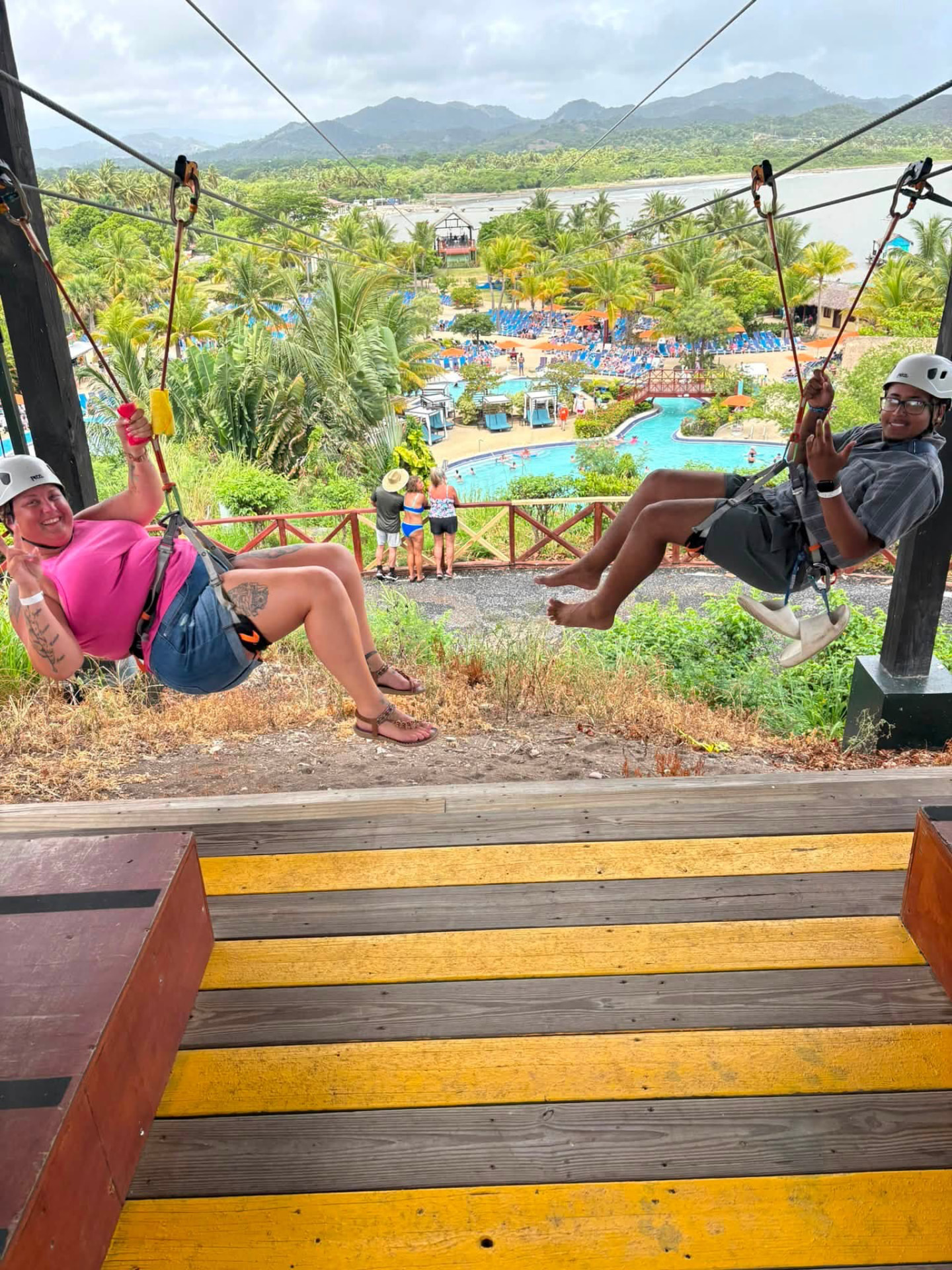 Jess ziplining above a tropical resort with a friend