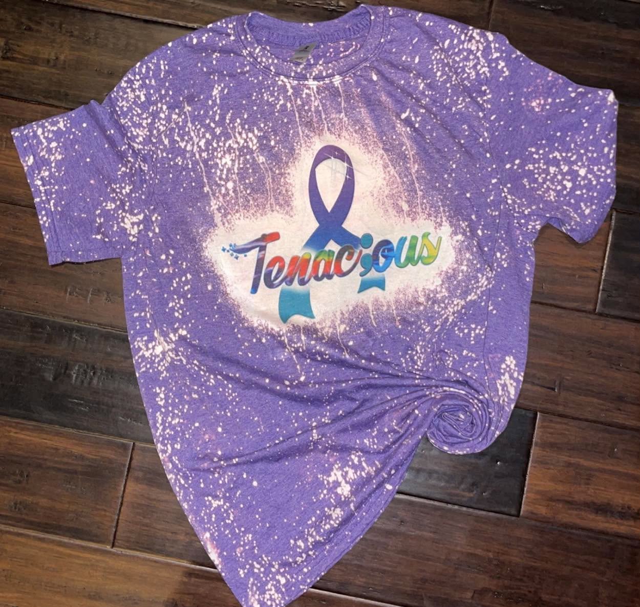 Purple bleached tee with a rainbow Tenac;ous awareness ribbon design